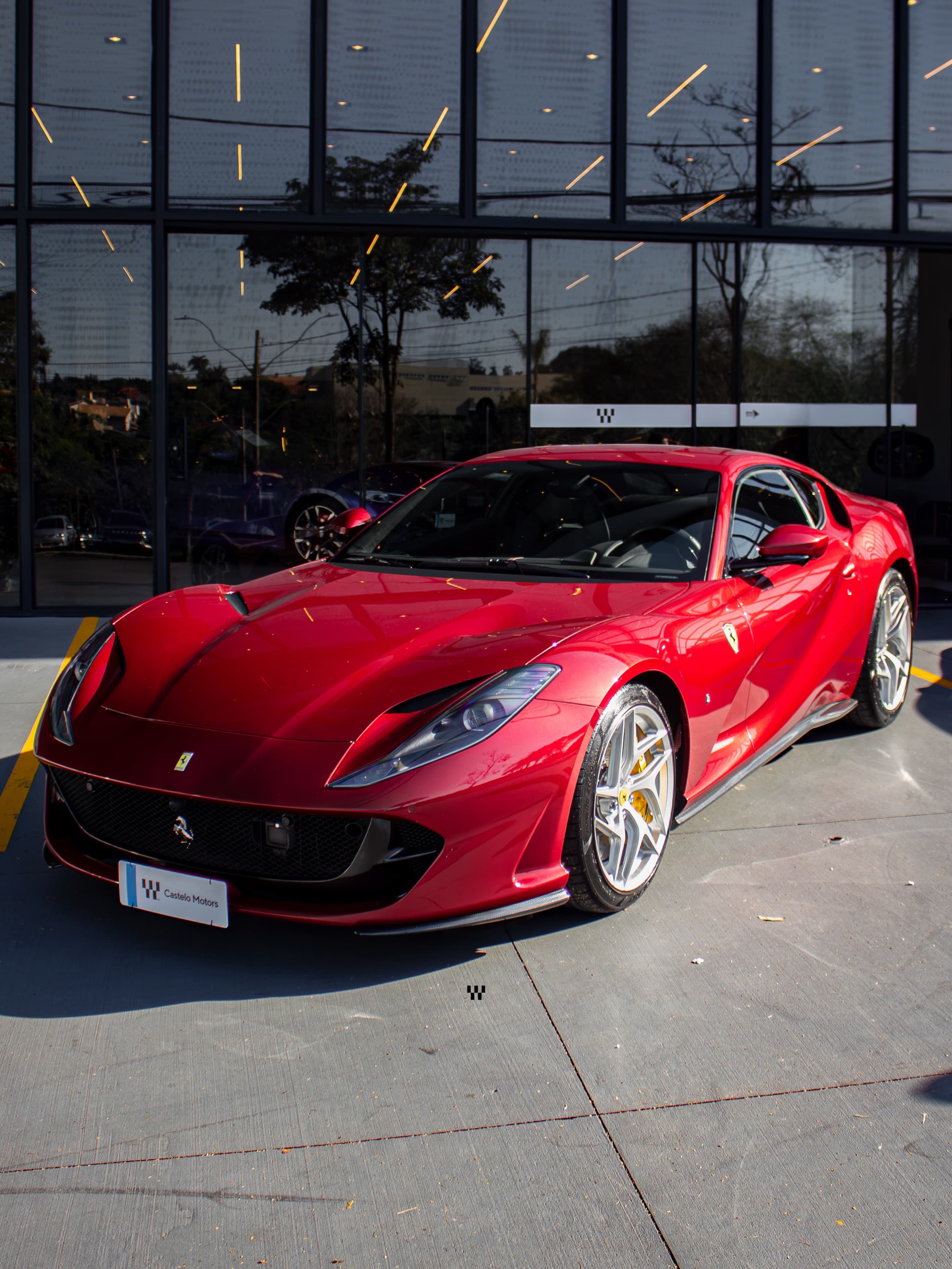 Ferrari 812 Superfast vermelha diante da fachada de vidro da Castelo Motors