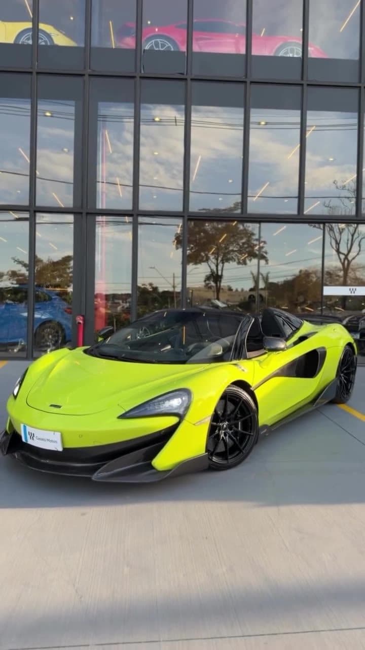 McLaren 600LT Spider verde-limão estacionada em frente à fachada da loja